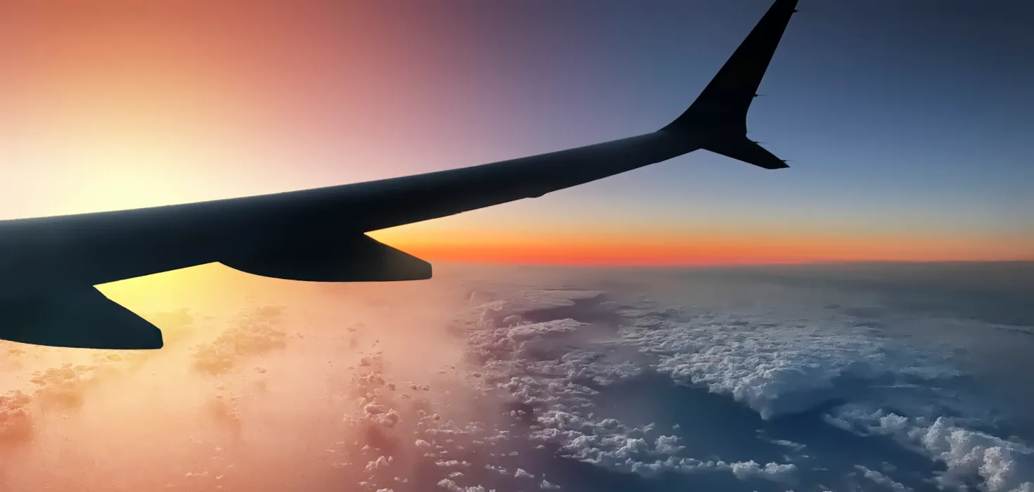 Wing of airplane flying over a sunset
