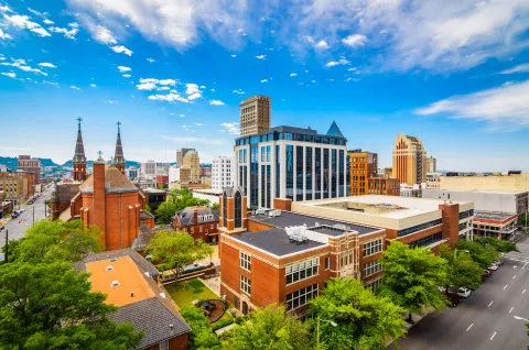 Cityscape of Birmingham with high buildings surrounded by green trees