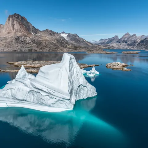 An iceberg floating among towering mountains